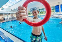 Osterferienspaß in den Bremer Bädern Bremer Bäder Hallenbad Südbad Junge hält ringförmiges Tauchgewicht vor Schwimmbecken