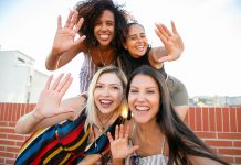 Internationaler Frauentag Vier junge Frauen die lächeln und ihre Hand in Richtung der Kamera halten